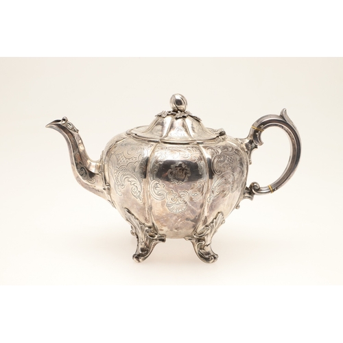 49 - A VICTORIAN ENGRAVED SILVER TEAPOT. Of melon form with engraved foliate scrolls, crested and initial... 