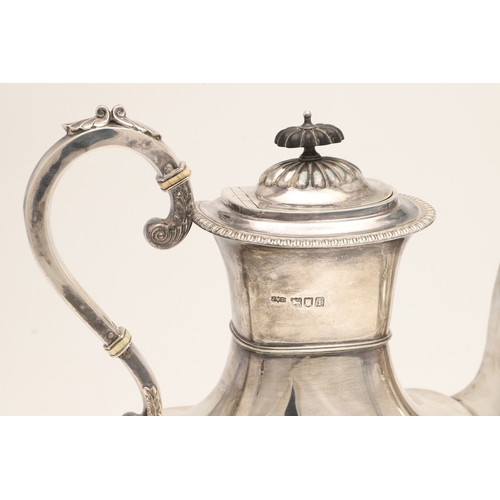 51 - AN EDWARDIAN SILVER FOUR PIECE TEA SET. Of half fluted oval form with scroll handles, gadrooned bord... 