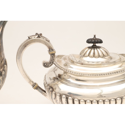 51 - AN EDWARDIAN SILVER FOUR PIECE TEA SET. Of half fluted oval form with scroll handles, gadrooned bord... 