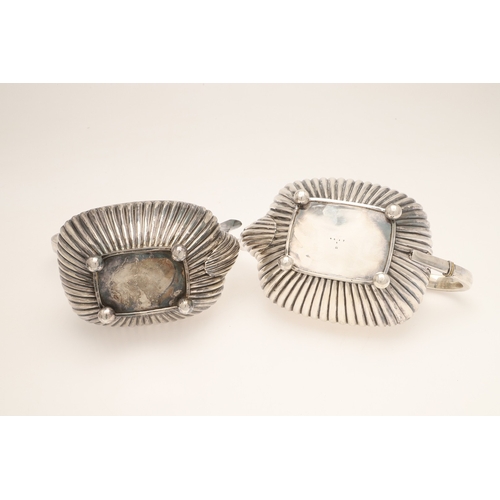 51 - AN EDWARDIAN SILVER FOUR PIECE TEA SET. Of half fluted oval form with scroll handles, gadrooned bord... 