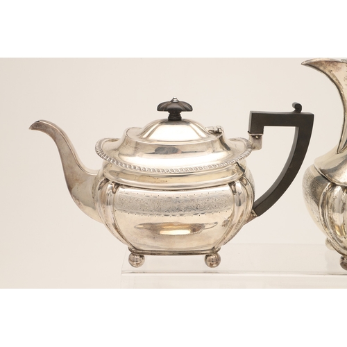 52 - AN EDWARDIAN SILVER FOUR PIECE TEA SET. Of shaped oblong form, with engraved foliate decoration, gad... 