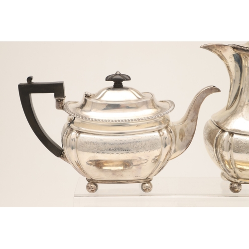 52 - AN EDWARDIAN SILVER FOUR PIECE TEA SET. Of shaped oblong form, with engraved foliate decoration, gad... 