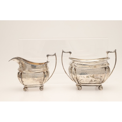 52 - AN EDWARDIAN SILVER FOUR PIECE TEA SET. Of shaped oblong form, with engraved foliate decoration, gad... 