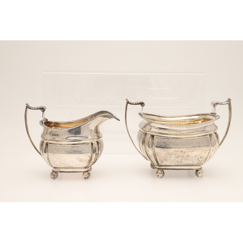 52 - AN EDWARDIAN SILVER FOUR PIECE TEA SET. Of shaped oblong form, with engraved foliate decoration, gad... 