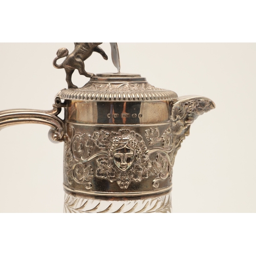 62 - A VICTORIAN SILVER MOUNTED GLASS CLARET JUG. Of bulbous form, the top with foliate vine and mask dec... 