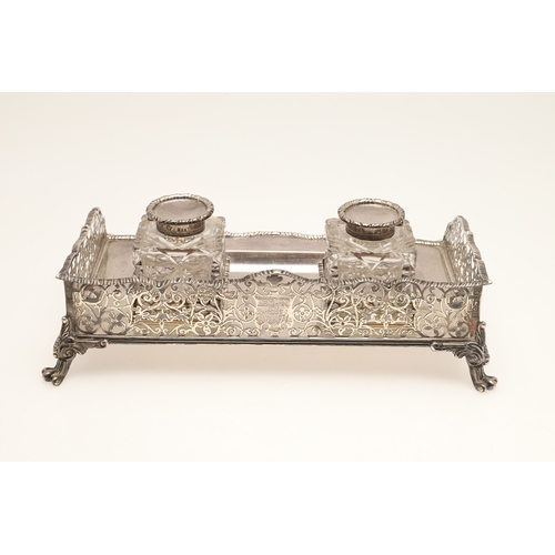 64 - A LATE VICTORIAN SILVER INK STAND. Of rectangular form with shaped front, gadrooned edging and pierc... 