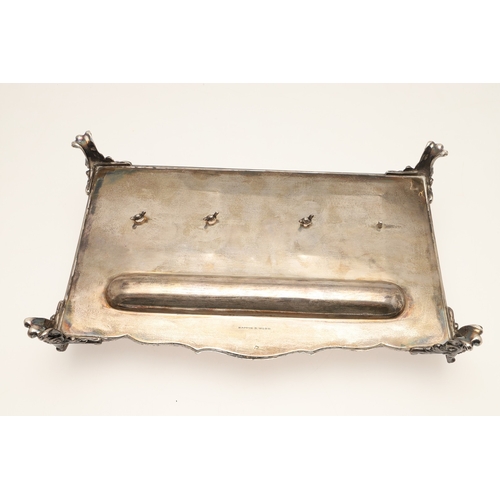 64 - A LATE VICTORIAN SILVER INK STAND. Of rectangular form with shaped front, gadrooned edging and pierc... 