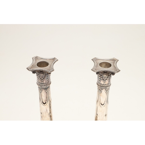 68 - A PAIR OF EDWARDIAN SILVER CANDLESTICKS OF CORINTHIAN COLUMN FORM. Hung swags & ribbons on gadrooned... 