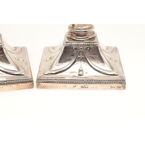 68 - A PAIR OF EDWARDIAN SILVER CANDLESTICKS OF CORINTHIAN COLUMN FORM. Hung swags & ribbons on gadrooned... 