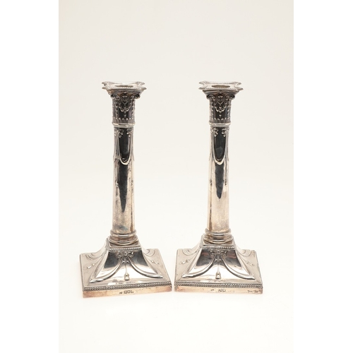 68 - A PAIR OF EDWARDIAN SILVER CANDLESTICKS OF CORINTHIAN COLUMN FORM. Hung swags & ribbons on gadrooned... 