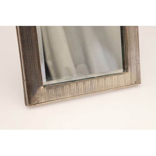 73 - A LATE EDWARDIAN SILVER EASEL DESK MIRROR. The engine turned rectangular frame with inset bevelled e... 