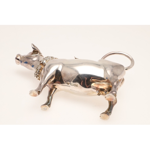 78 - A SILVER COW CREAMER BY GARRARD & CO LTD. The cow decorated with floral wreaths and insect to the li... 