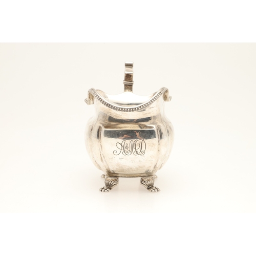 83 - A GEORGE III IRISH SILVER CREAM JUG. With gadrooned rim and stood on paw feet, engraved initials A &... 