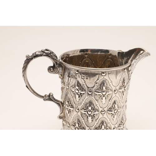 85 - A VICTORIAN SILVER JUG. Of rounded form, with repousse flowerhead decoration and scroll handle, heig... 