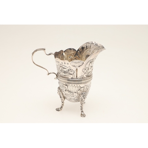 89 - A LATE VICTORIAN IRISH STYLE SILVER CREAM JUG. With later chased decoration of flora and fauna, scro... 