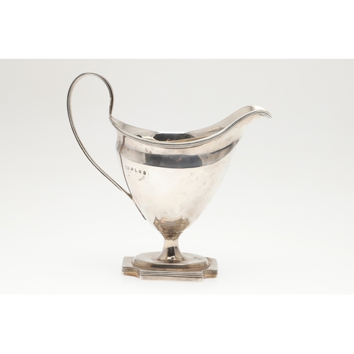 29 - A GEORGE III SILVER HELMET SHAPED CREAM JUG. The helmet shape bowl with handle, on a rectangular bas... 