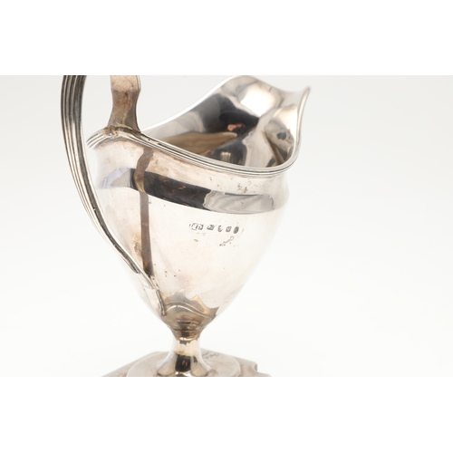 29 - A GEORGE III SILVER HELMET SHAPED CREAM JUG. The helmet shape bowl with handle, on a rectangular bas... 