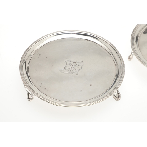 37 - A PAIR OF SMALL GEORGE III SILVER SALVERS. Of circular form with central engraved crest, raised on t... 