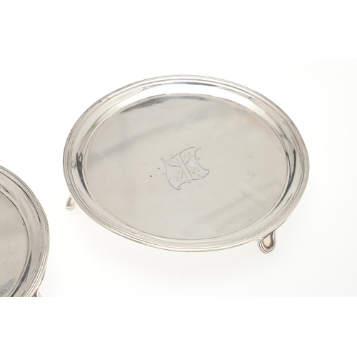 37 - A PAIR OF SMALL GEORGE III SILVER SALVERS. Of circular form with central engraved crest, raised on t... 