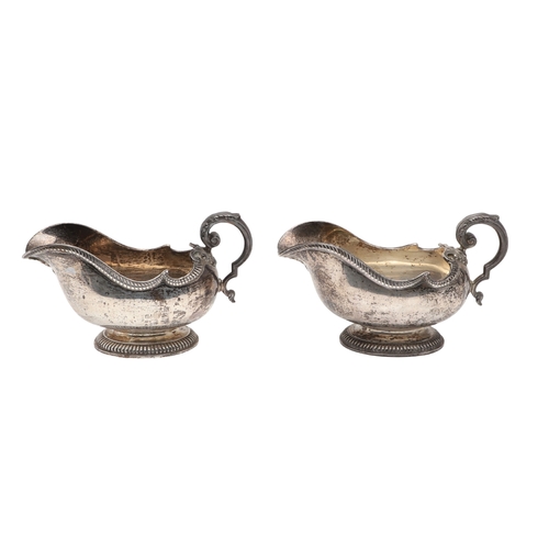45 - A PAIR OF GEORGE V SILVER SAUCE BOATS. Featuring deep oval shaped bowls with broad spouts, gadrooned... 