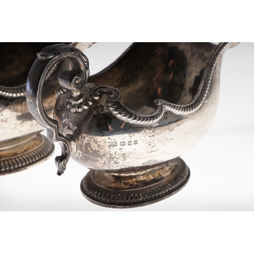 45 - A PAIR OF GEORGE V SILVER SAUCE BOATS. Featuring deep oval shaped bowls with broad spouts, gadrooned... 