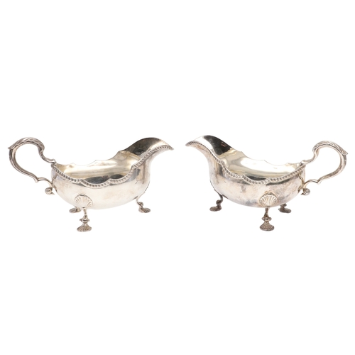 46 - A PAIR OF GEORGIAN STYLE SILVER GRAVY BOATS. Featuring deep oval shaped bowls with broad spouts, gad... 