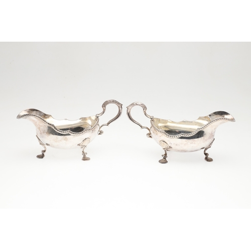 46 - A PAIR OF GEORGIAN STYLE SILVER GRAVY BOATS. Featuring deep oval shaped bowls with broad spouts, gad... 