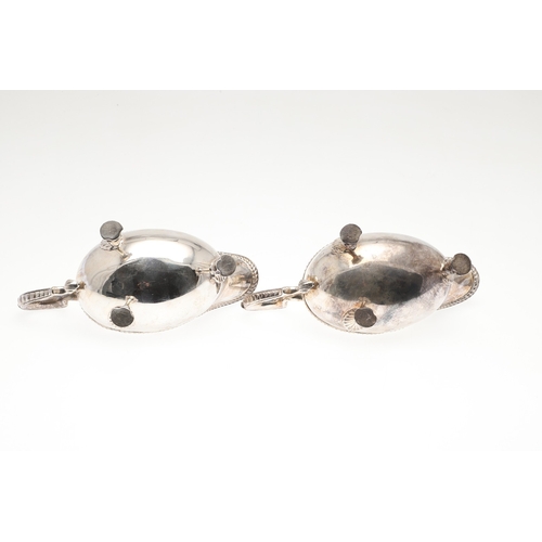 46 - A PAIR OF GEORGIAN STYLE SILVER GRAVY BOATS. Featuring deep oval shaped bowls with broad spouts, gad... 