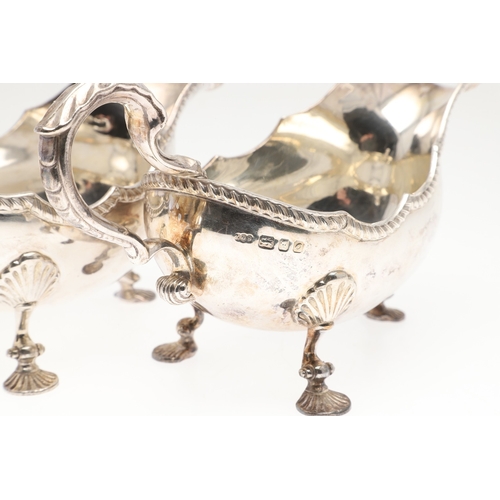 46 - A PAIR OF GEORGIAN STYLE SILVER GRAVY BOATS. Featuring deep oval shaped bowls with broad spouts, gad... 