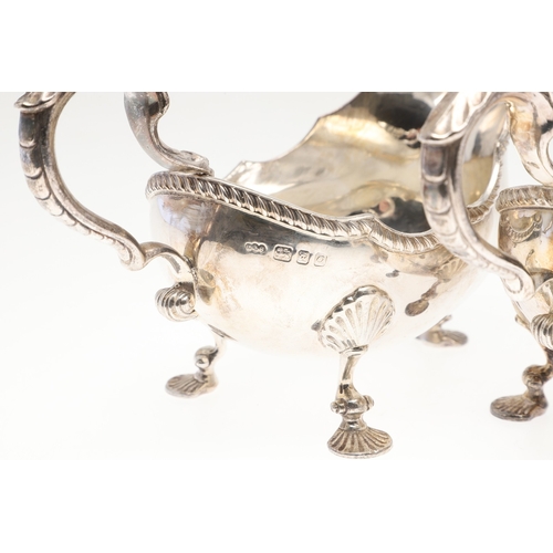 46 - A PAIR OF GEORGIAN STYLE SILVER GRAVY BOATS. Featuring deep oval shaped bowls with broad spouts, gad... 