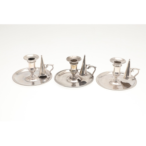 51 - A TRIO OF GEORGE III SILVER CHAMBERSTICKS. With gadrooned decoration and acanthus leaf thumb piece, ... 