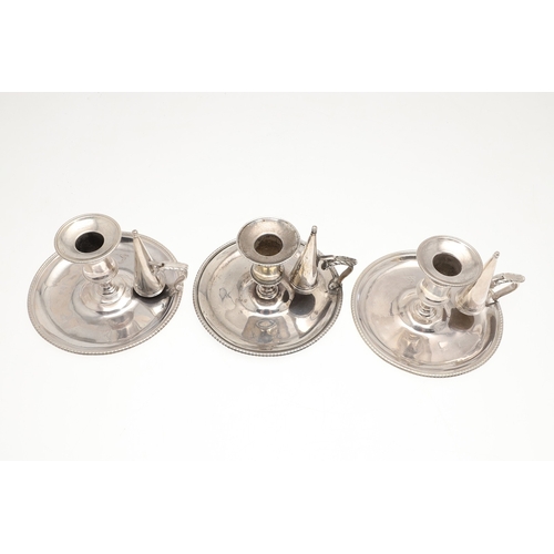 51 - A TRIO OF GEORGE III SILVER CHAMBERSTICKS. With gadrooned decoration and acanthus leaf thumb piece, ... 