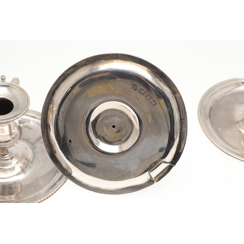 51 - A TRIO OF GEORGE III SILVER CHAMBERSTICKS. With gadrooned decoration and acanthus leaf thumb piece, ... 