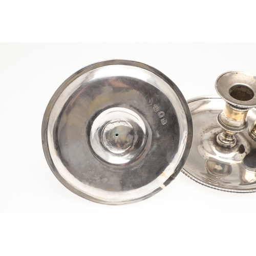 51 - A TRIO OF GEORGE III SILVER CHAMBERSTICKS. With gadrooned decoration and acanthus leaf thumb piece, ... 