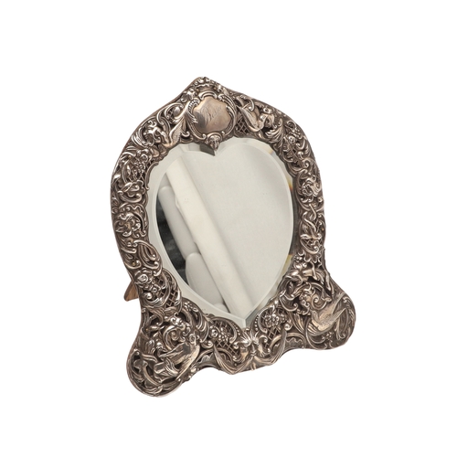 56 - AN EDWARDIAN SILVER ART NOUVEAU STYLE TABLE MIRROR. Of shaped form, the bevelled edge heart shape mi... 