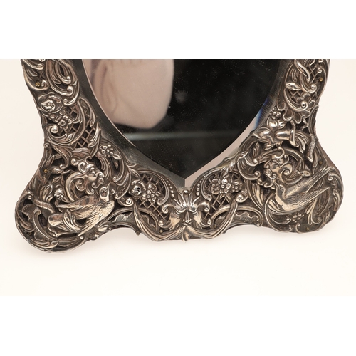 56 - AN EDWARDIAN SILVER ART NOUVEAU STYLE TABLE MIRROR. Of shaped form, the bevelled edge heart shape mi... 