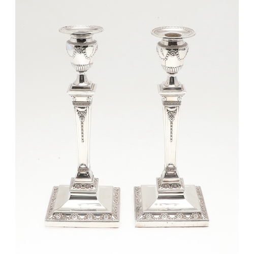 60 - A PAIR OF VICTORIAN SILVER CANDLESTICKS. Each candlestick with a beaded circular sconce, urn shaped ... 