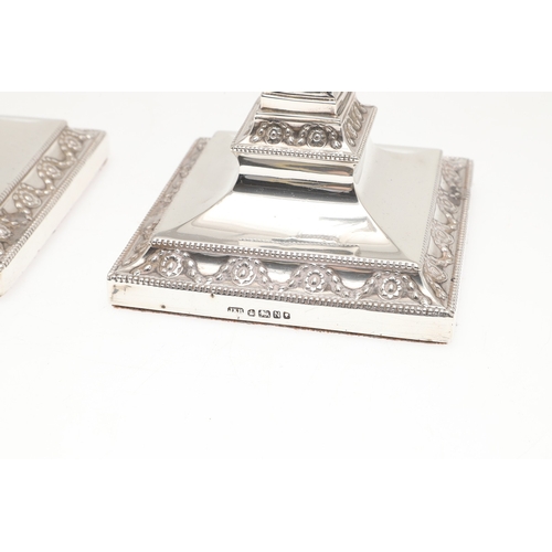 60 - A PAIR OF VICTORIAN SILVER CANDLESTICKS. Each candlestick with a beaded circular sconce, urn shaped ... 