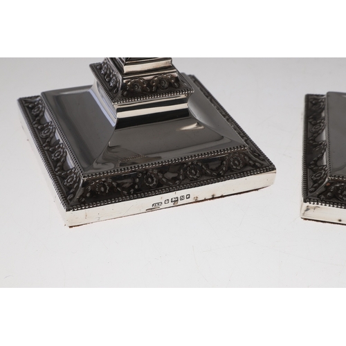 60 - A PAIR OF VICTORIAN SILVER CANDLESTICKS. Each candlestick with a beaded circular sconce, urn shaped ... 