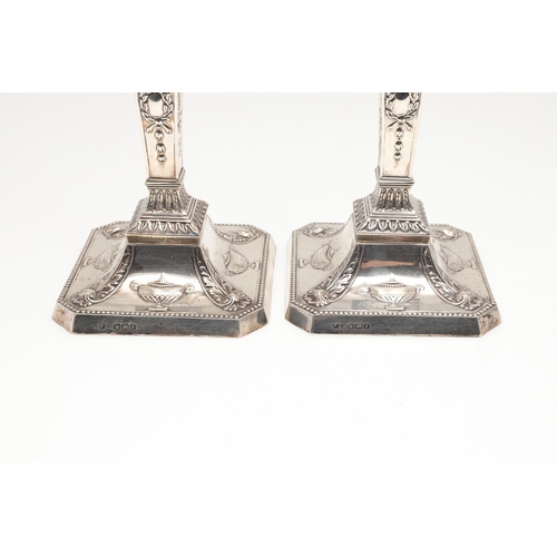 61 - A PAIR OF EARLY 20TH CENTURY FILLED SILVER CANDLESTICKS. In the Adam style, each candlestick being d... 