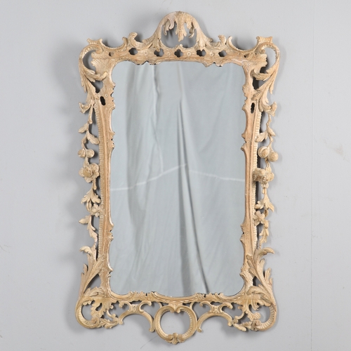 534 - AN 18TH CENTURY CARVED LIMEWOOD WALL MIRROR. the carved foliate and C-scroll surround to a later pla... 
