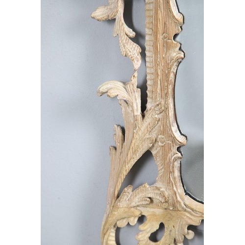 534 - AN 18TH CENTURY CARVED LIMEWOOD WALL MIRROR. the carved foliate and C-scroll surround to a later pla... 