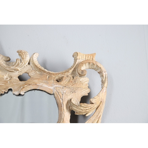 534 - AN 18TH CENTURY CARVED LIMEWOOD WALL MIRROR. the carved foliate and C-scroll surround to a later pla... 