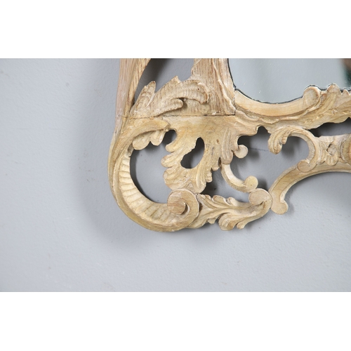 534 - AN 18TH CENTURY CARVED LIMEWOOD WALL MIRROR. the carved foliate and C-scroll surround to a later pla... 