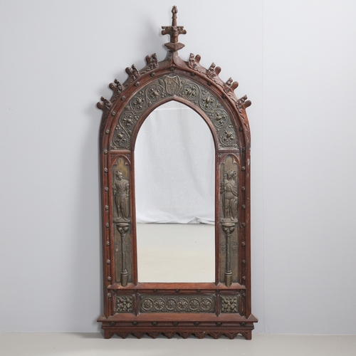 543 - A LATE 19TH CENTURY 'GOTHIC' OAK AND BRASS WALL MIRROR. the carved arched surround to pressed brass ... 