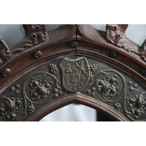 543 - A LATE 19TH CENTURY 'GOTHIC' OAK AND BRASS WALL MIRROR. the carved arched surround to pressed brass ... 