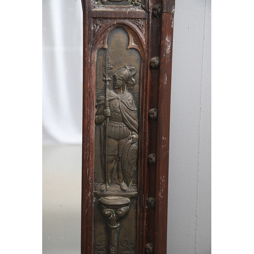 543 - A LATE 19TH CENTURY 'GOTHIC' OAK AND BRASS WALL MIRROR. the carved arched surround to pressed brass ... 