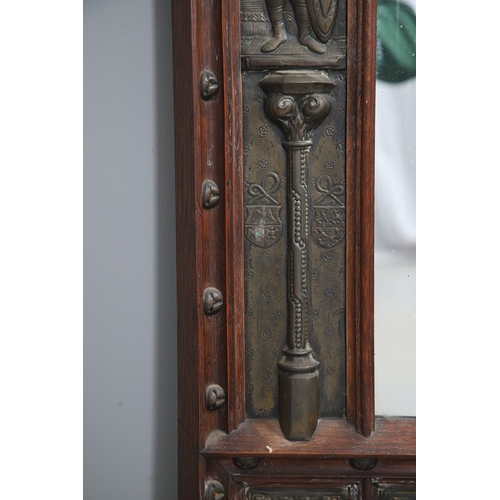 543 - A LATE 19TH CENTURY 'GOTHIC' OAK AND BRASS WALL MIRROR. the carved arched surround to pressed brass ... 