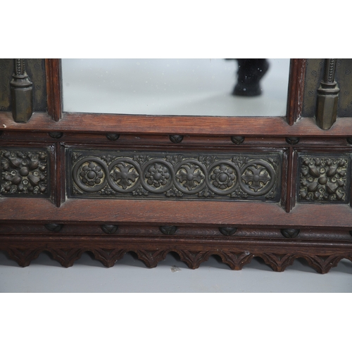 543 - A LATE 19TH CENTURY 'GOTHIC' OAK AND BRASS WALL MIRROR. the carved arched surround to pressed brass ... 
