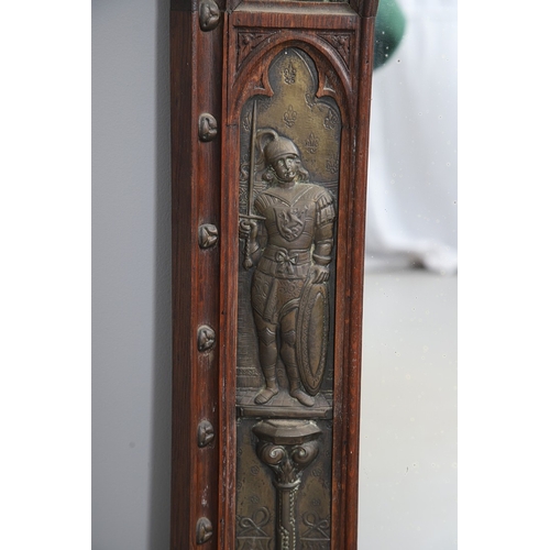 543 - A LATE 19TH CENTURY 'GOTHIC' OAK AND BRASS WALL MIRROR. the carved arched surround to pressed brass ... 